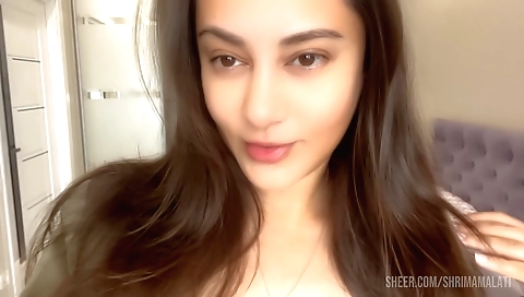 A hot brunette sits in the bed with her hand on her pussy